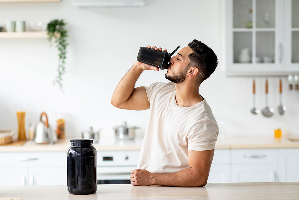 A man drinks a supplement shake in a modern kitchen