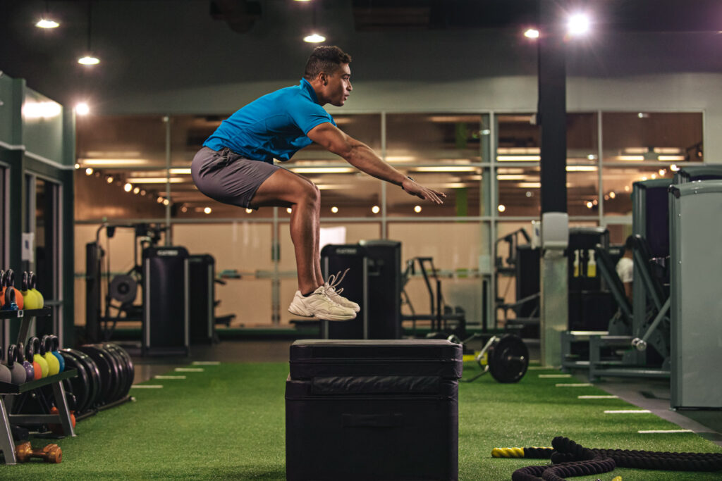 Man jumping on a plyometric box at a YouFit Gym.