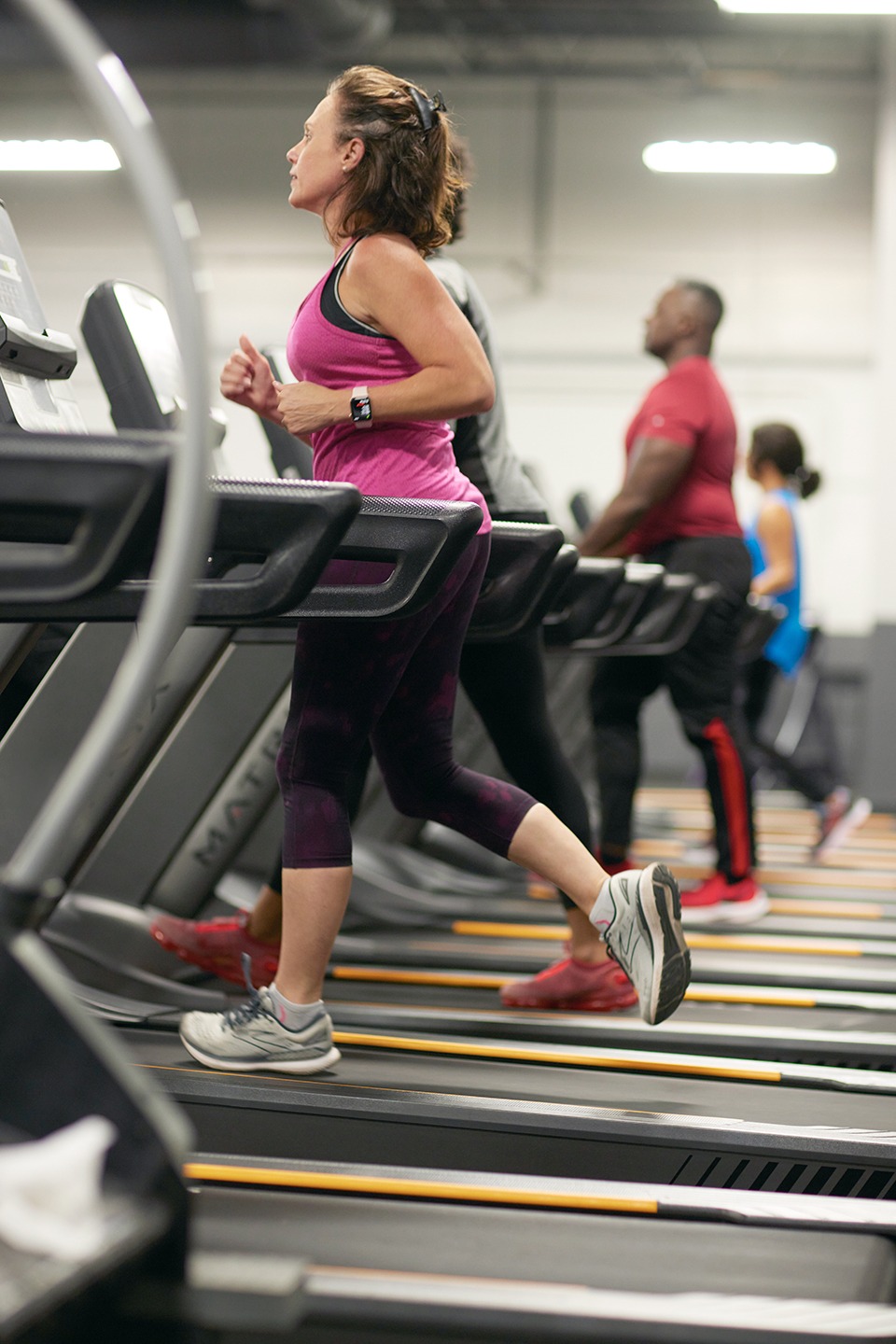 people running on treadmills with a woman in the foreground