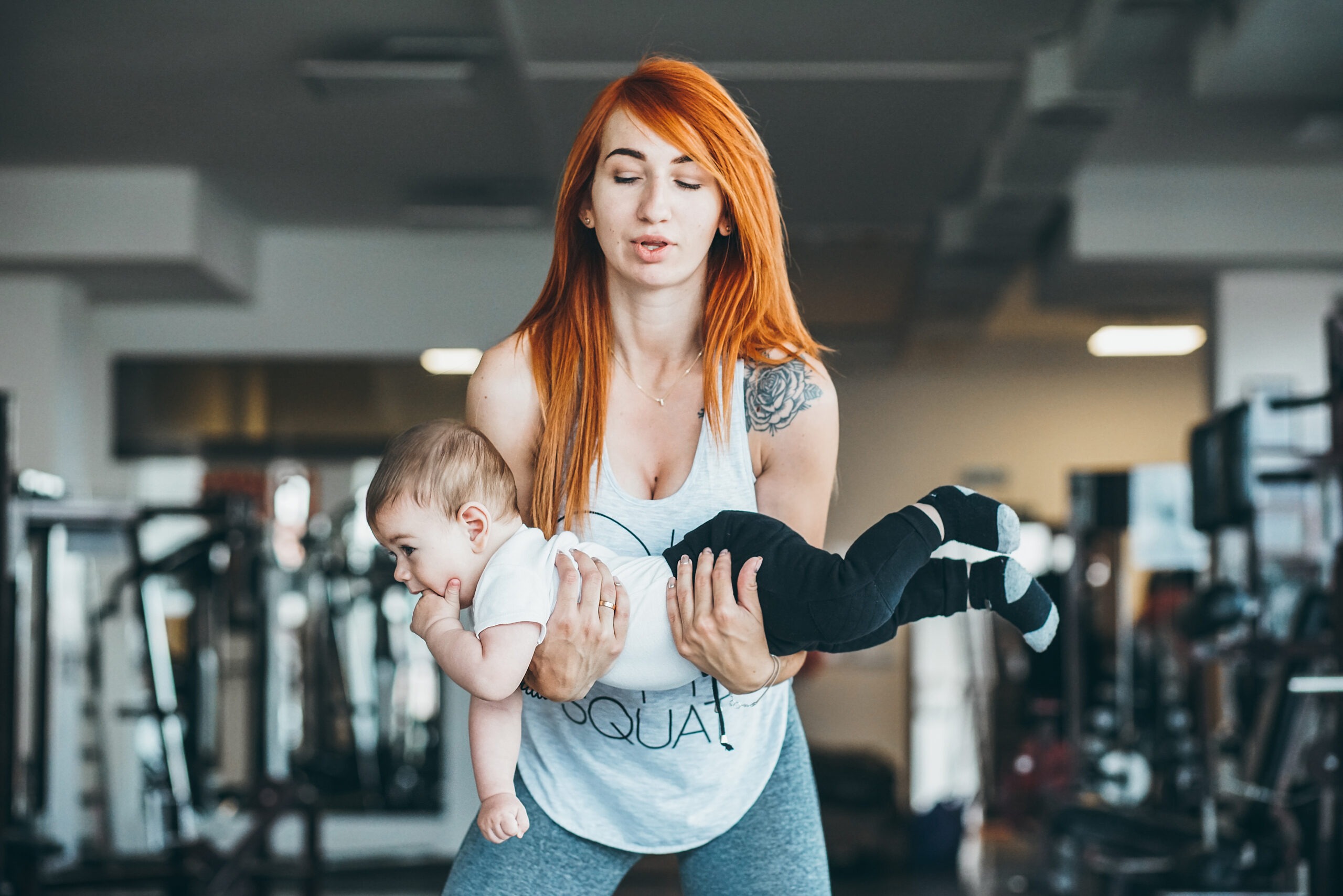 young training mother carefully deadlifts her toddler
