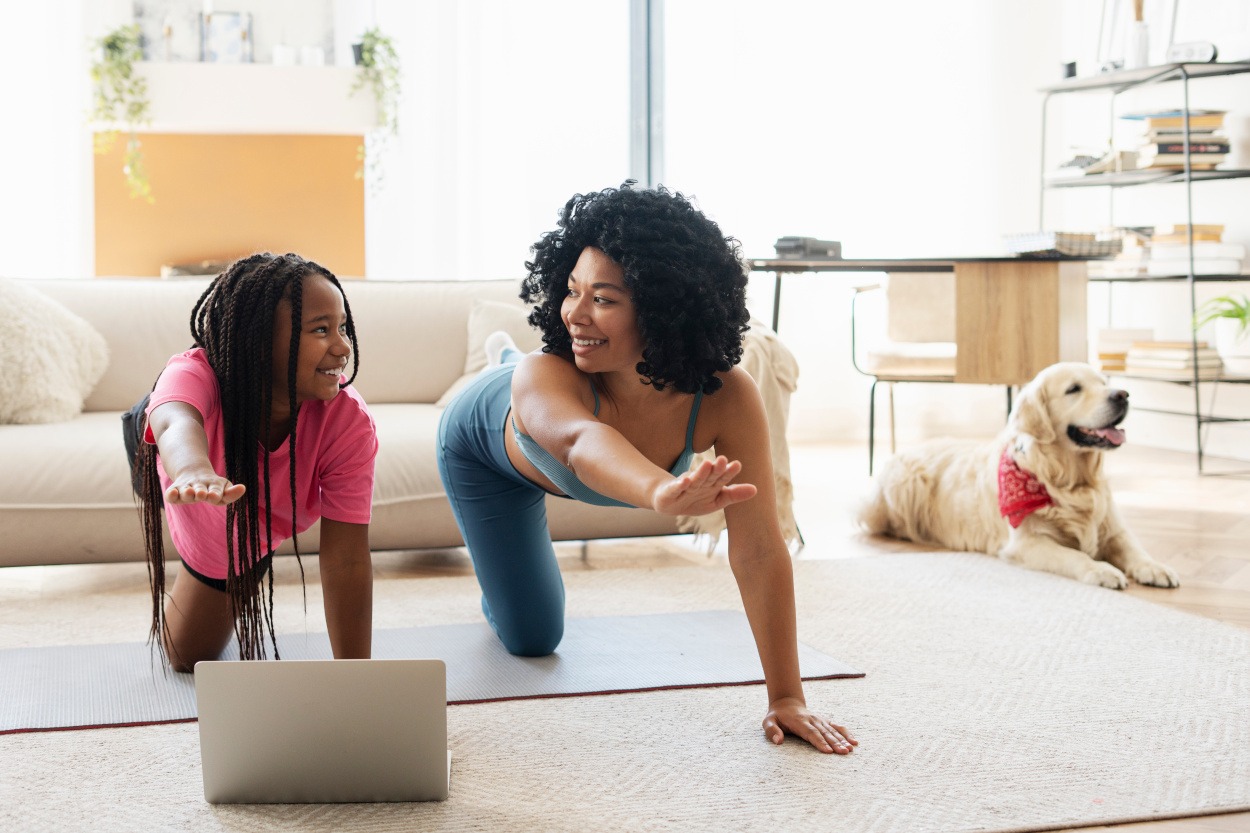 mother and daughter practice yoga with family dog nearby