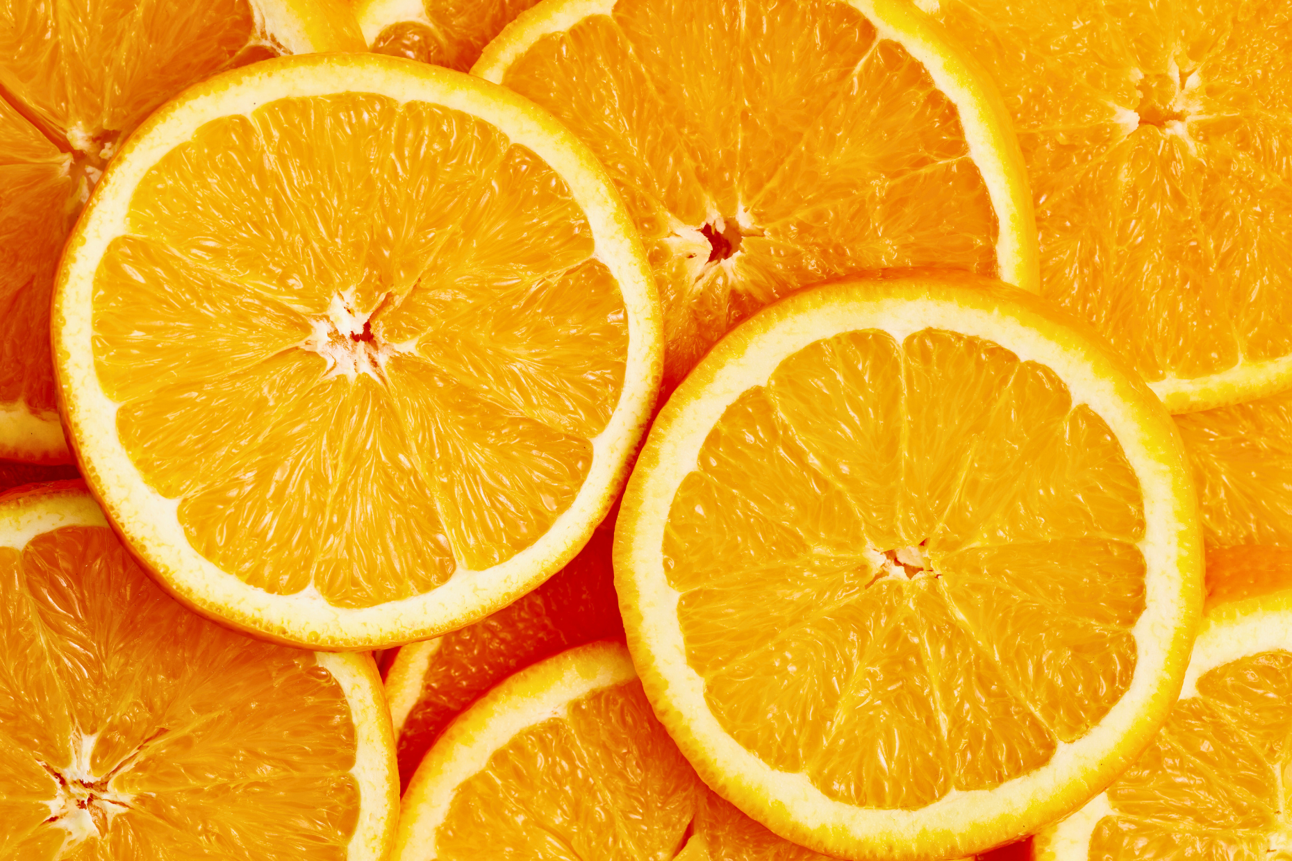 Close-up of several overlapping orange slices, showcasing their juicy, vibrant flesh and white rinds. The image highlights the texture and freshness that make oranges a delicious boost for your immune system.