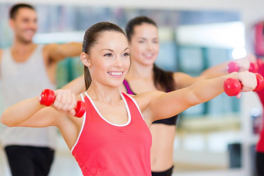 Woman in an exercise class raising up dumbbells in each hand